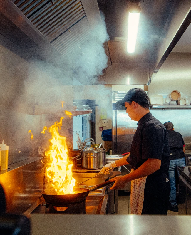 Un chef cuisinier asiatique devant son wok